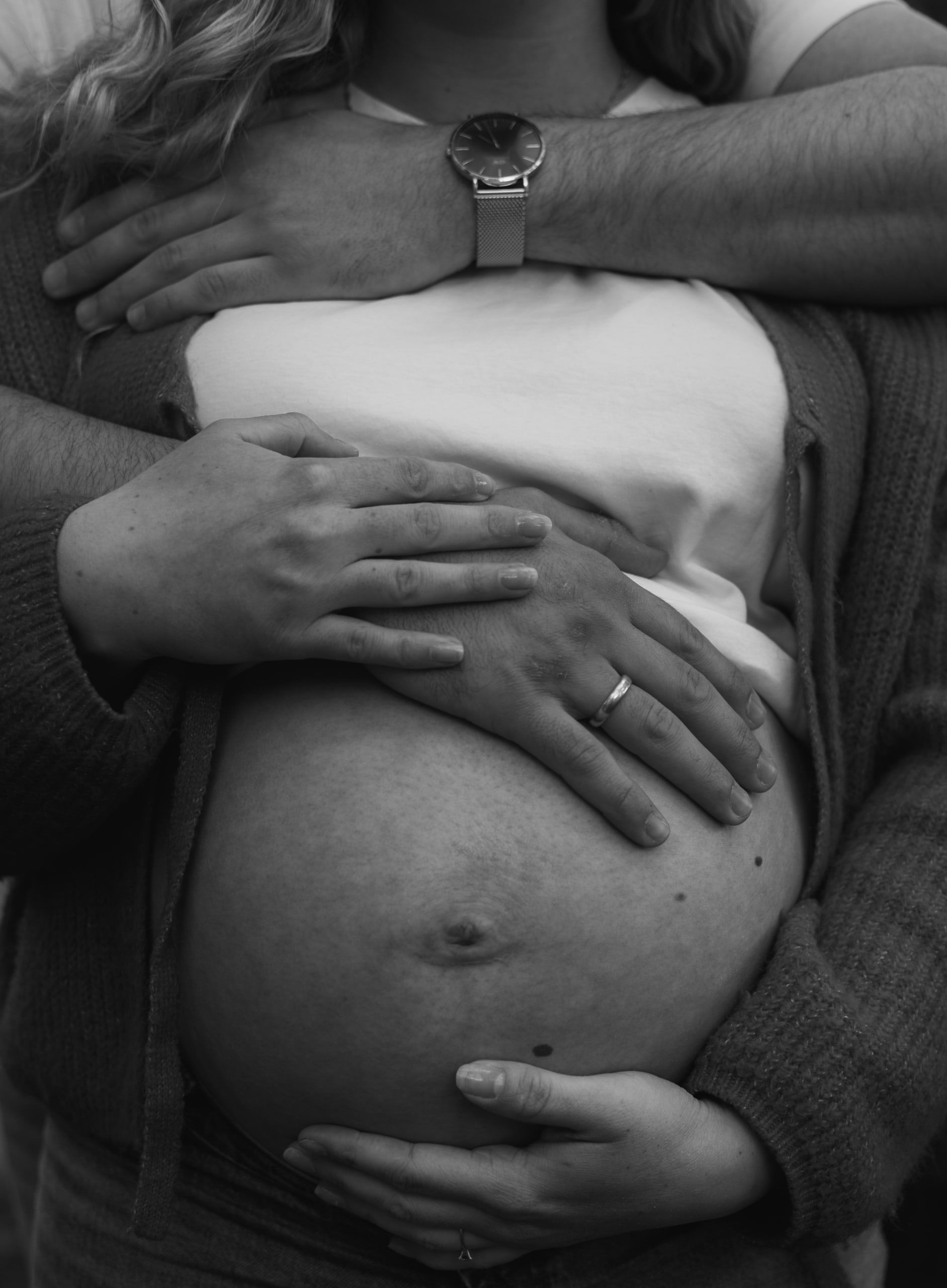 Svart-hvitt bilde av hender med giftering som holder rundt en gravid mage